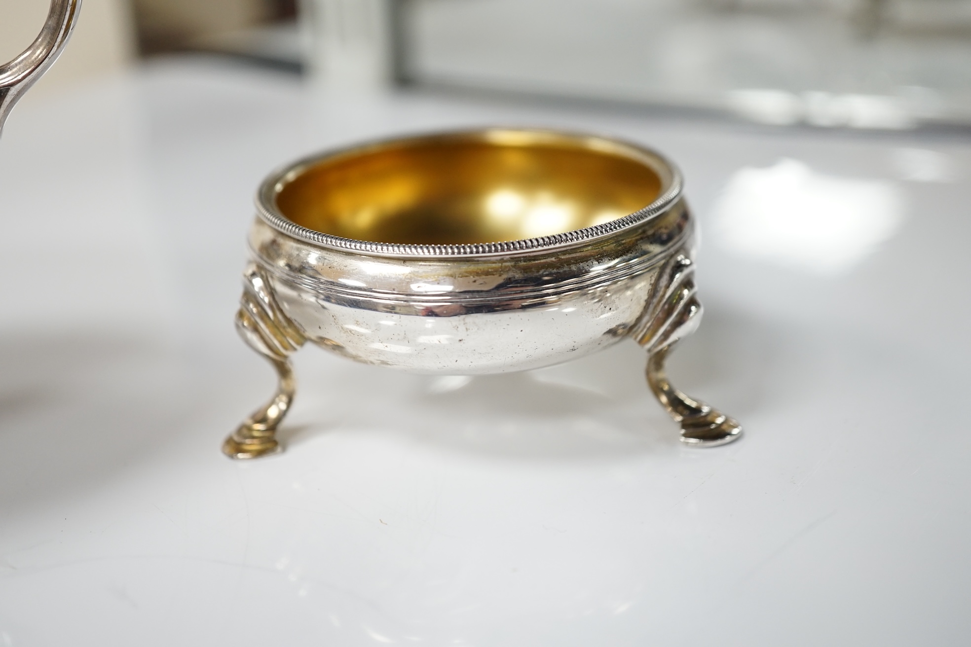 A pair of George III silver cauldron salts, London, 1765, with a pair of later Georgian mustard ladles, together with a late Victorian silver sauceboat. Condition - fair to good